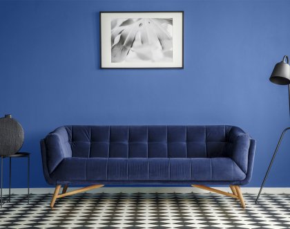 "Granatowa sofa na tle niebieskiej ściany, czarno-białe dodatki."
